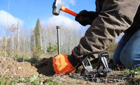 a man is driving a stake into the ground for his staking system